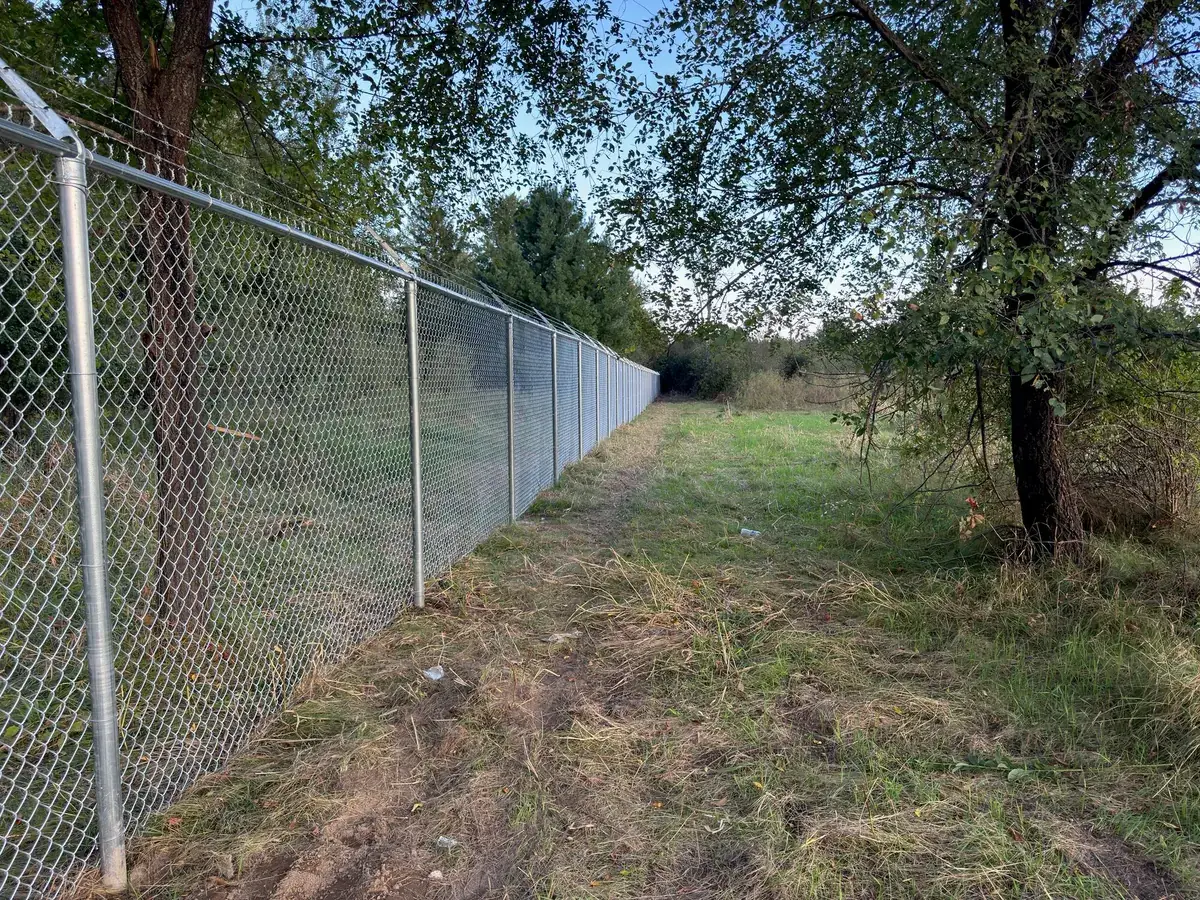 Chain-link site perimeter along a treeline