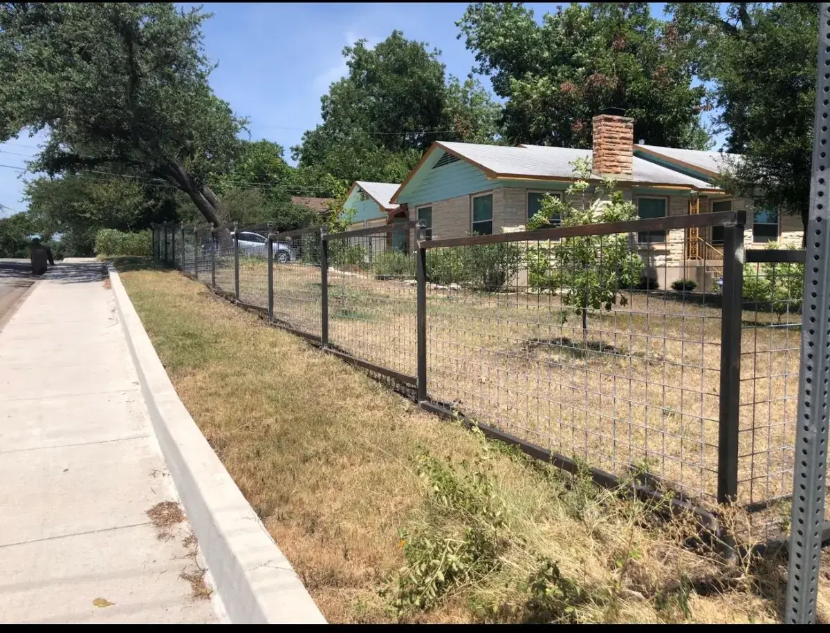Steel-frame hog-wire fence at a stone home